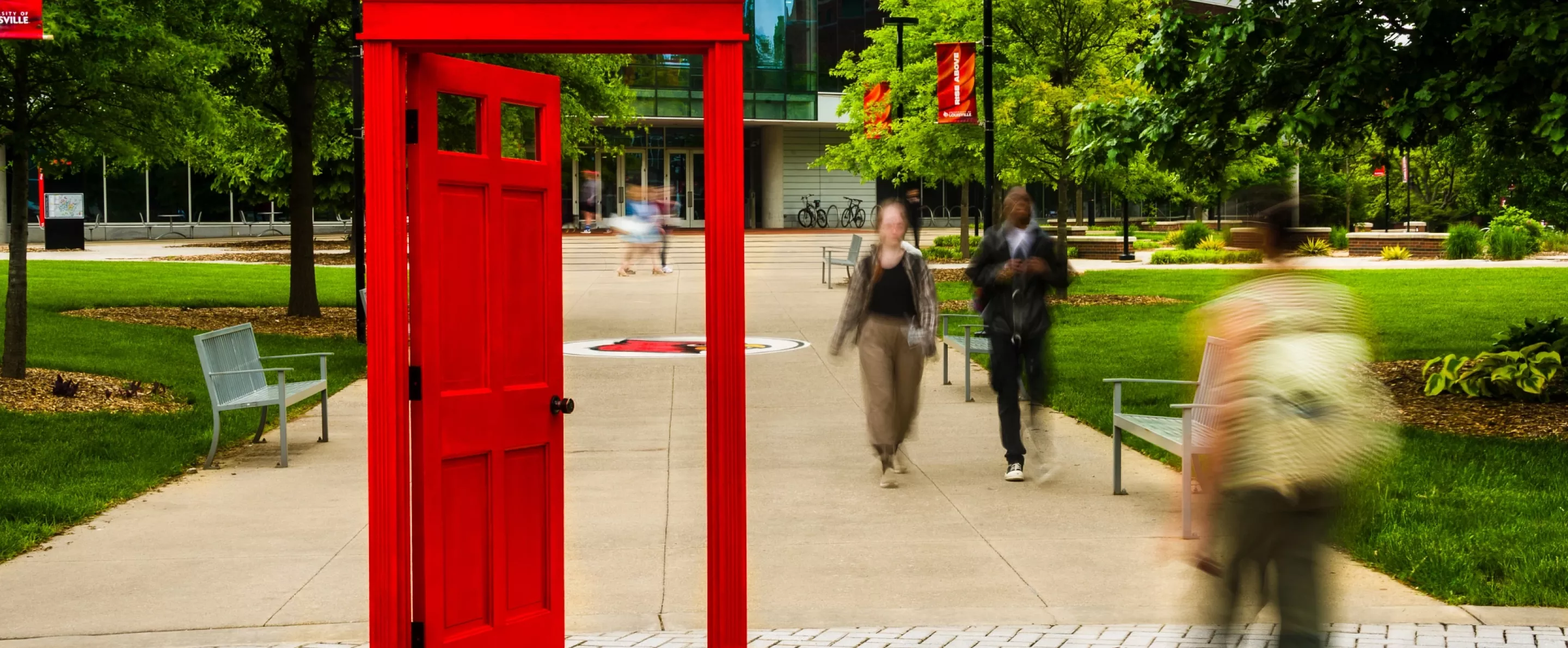 A red doorway on campus with students and an academic building