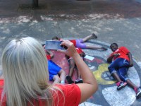 Woman taking picture of kids laying on Cardinal bird logo on concrete