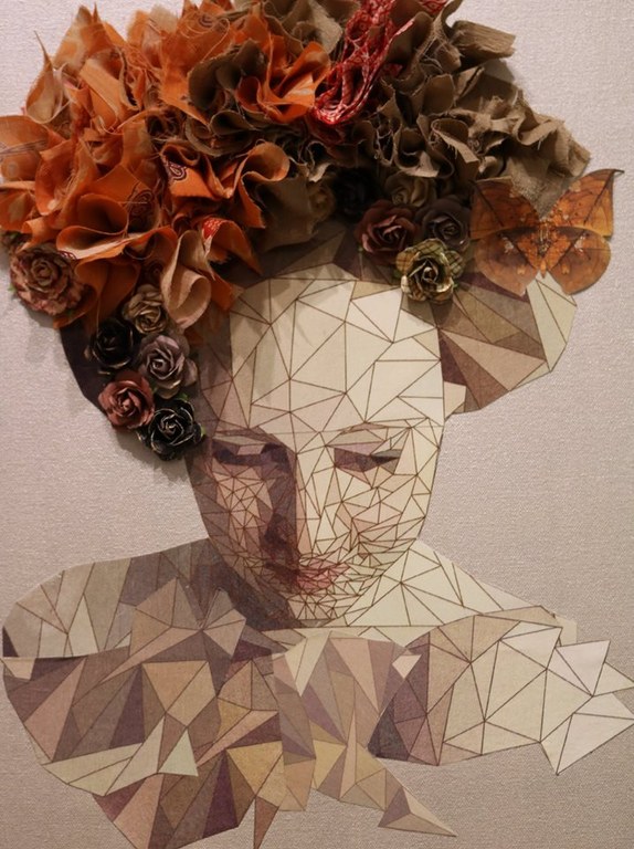 An art portrait made up of geometric angular patterns that construct the face and with fabric folded and spiraled into a floral pattern ornamenting the head.