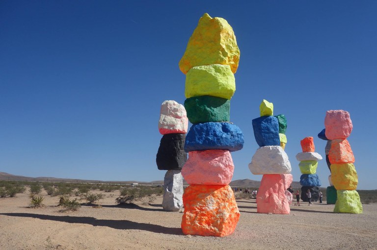 An outdoor installation of colorful/dyed rocks stacked.