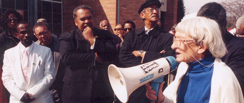 Anne Braden with megaphone speaking to crowd of African Americans