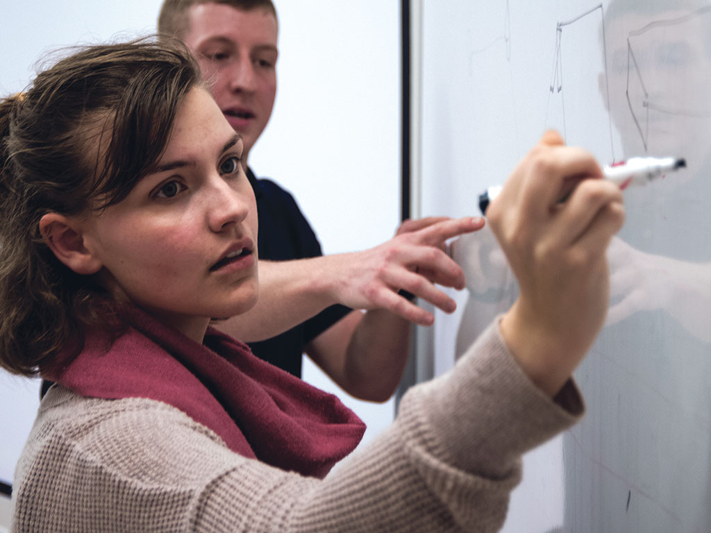 Close up of design students writing on whiteboard