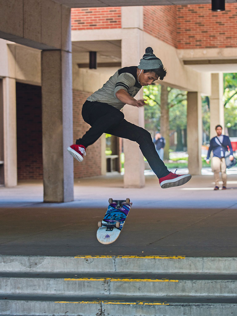 A student skateboarding on campus