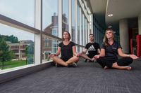 photo of 3 thin white people sitting in yoga pose practicing mindfulness