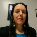 Heather N. Hill, a Native American woman with long dark brown hair, sits in an office.
