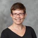 head shot of a white woman with short hair wearing a black shirt and red glasses Stephanie Kerschbaum