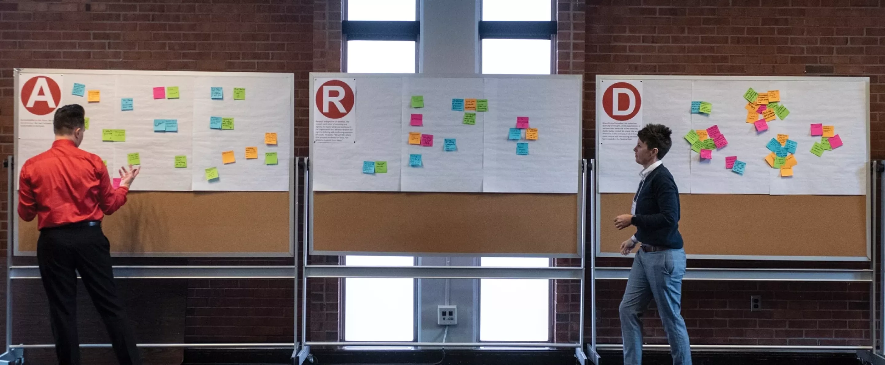 2 people brainstorming with sticky notes on boards