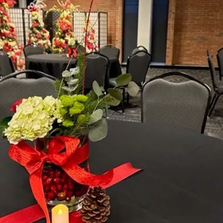 Ballroom with projector screen and multiple rows of tables and chairs