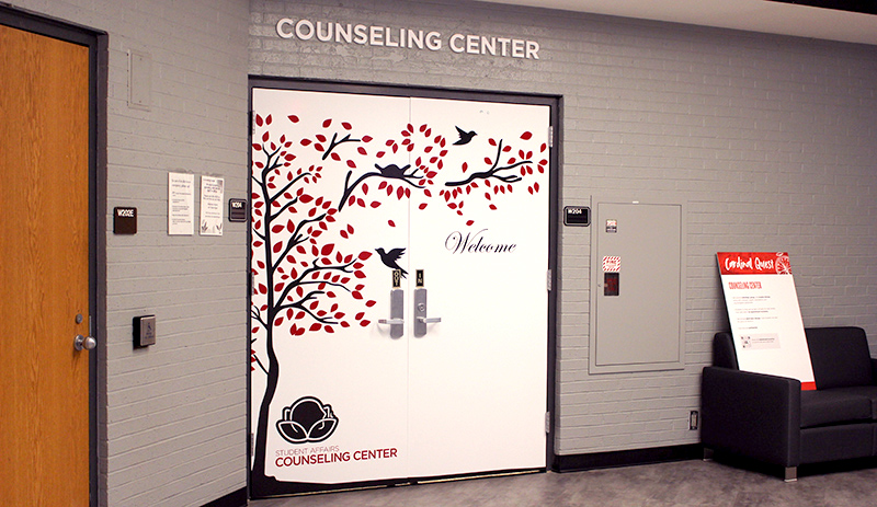Counseling Center doors featuring graphic of a tree with birds flying and perched and leaves blowing in the wind.