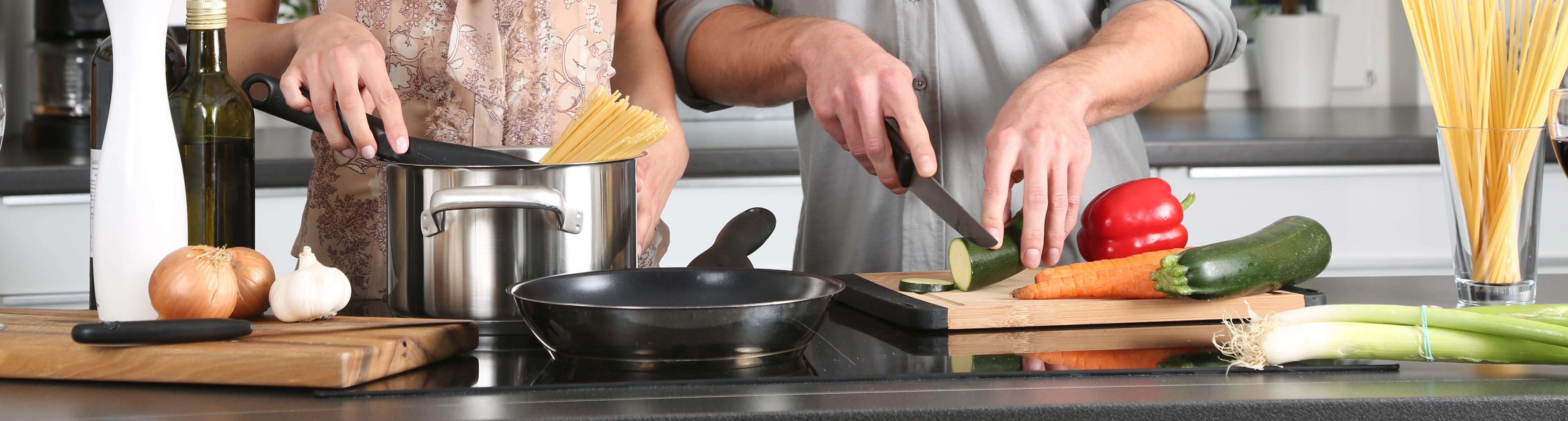 two people cooking pasta and vegetables together
