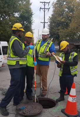 4 men inspecting a local sewer