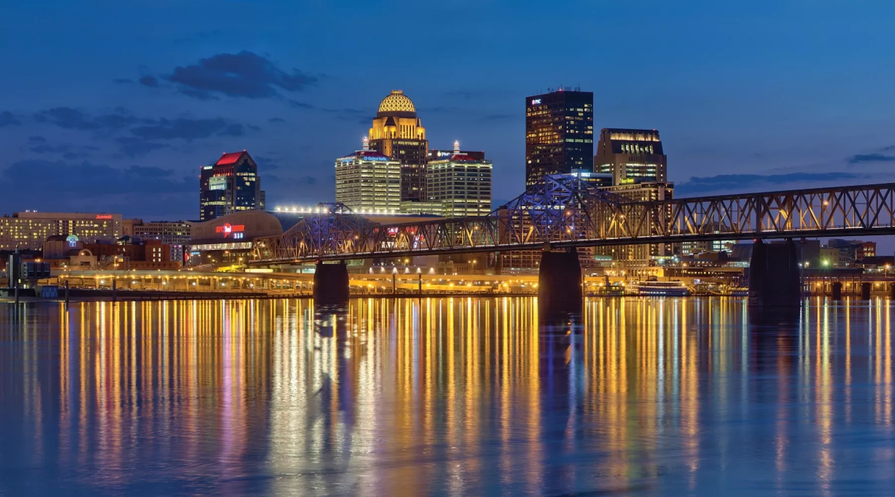 Nighttime skyline photo of the Louisville waterfront with light reflections in the Ohio River
