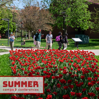 photo of students on campus during the summer with red flowers. Click to view summer camps and conferences housing information