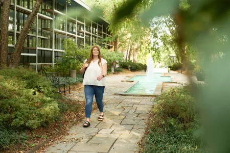 Student walking near fountain area holding a backpack.