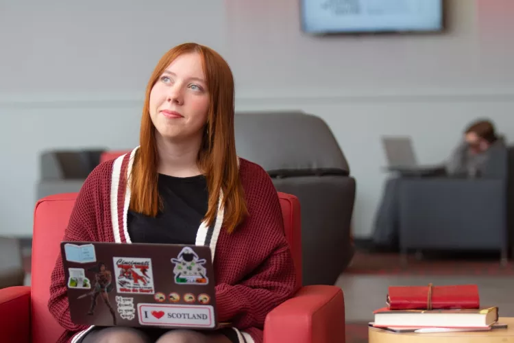A student pauses in thought while working on a laptop in the Belknap Academic Building