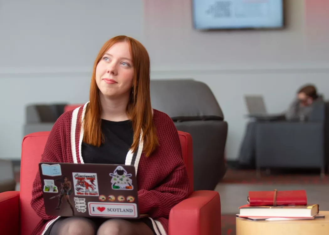 A student pauses in thought while working on a laptop in the Belknap Academic Building