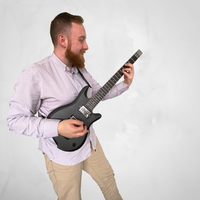 Chris Millett pictured with grey background playing black Jamstik Studio MIDI guitar