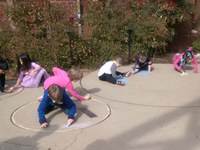 Kids chalk coloring planet models built into patio of the planetarium