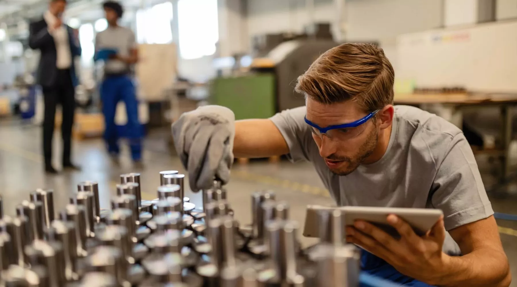 Young steel worker examining manufactured rod cylinder