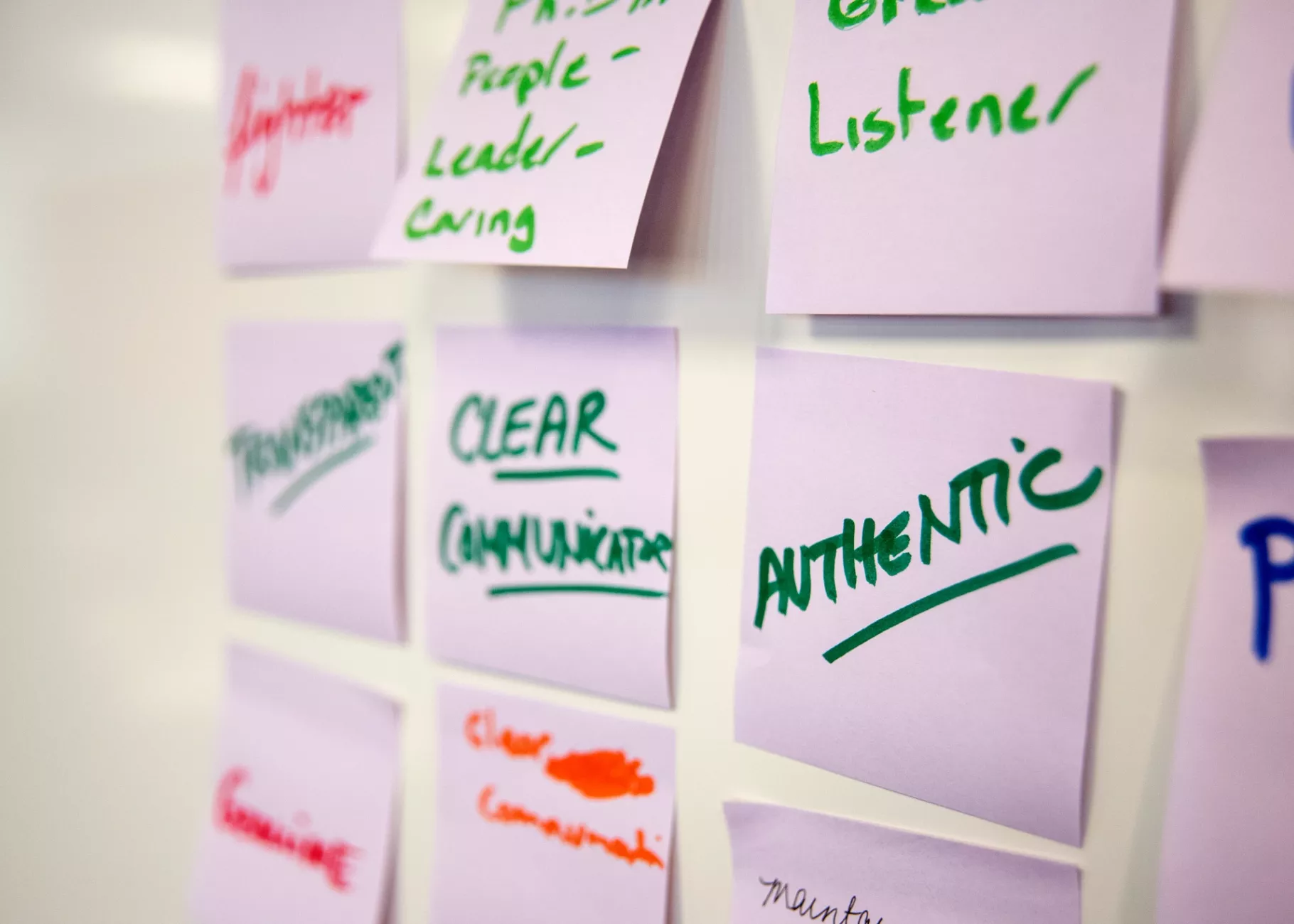 Close-up of sticky notes in an exercise. Notes in focus read "authentic, clear communication, great listener, transparent"