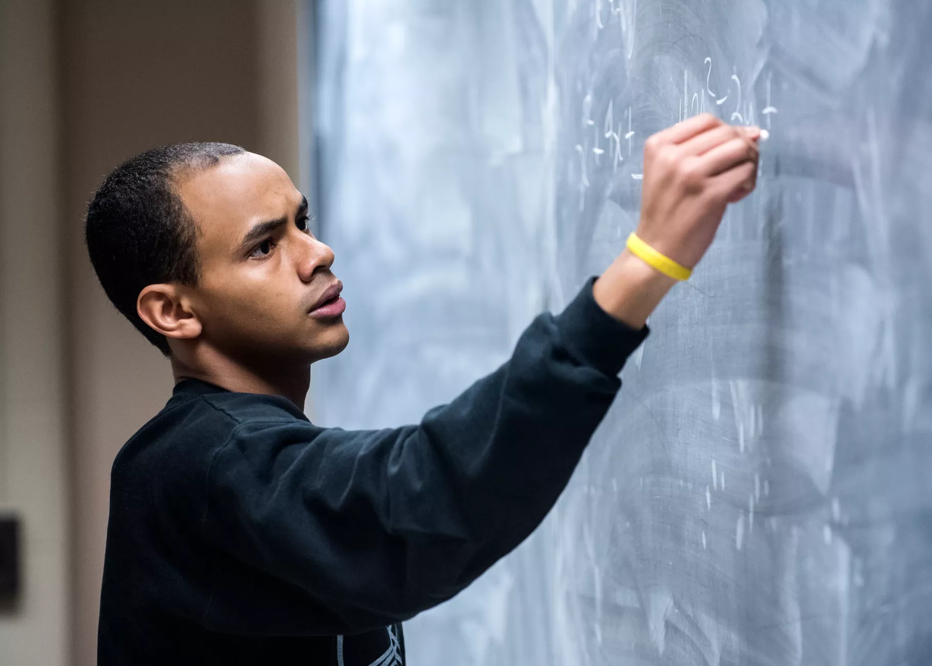 Professor writes out math problems on the chalk board