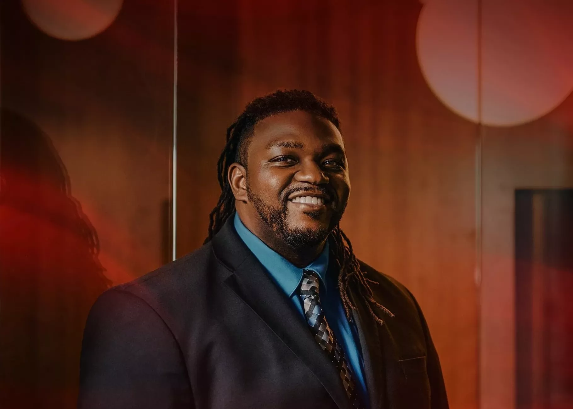 A smiling man in a dark suit posed in an office setting.