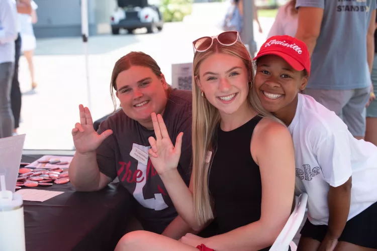 Three students smiling at the camera during Homecoming