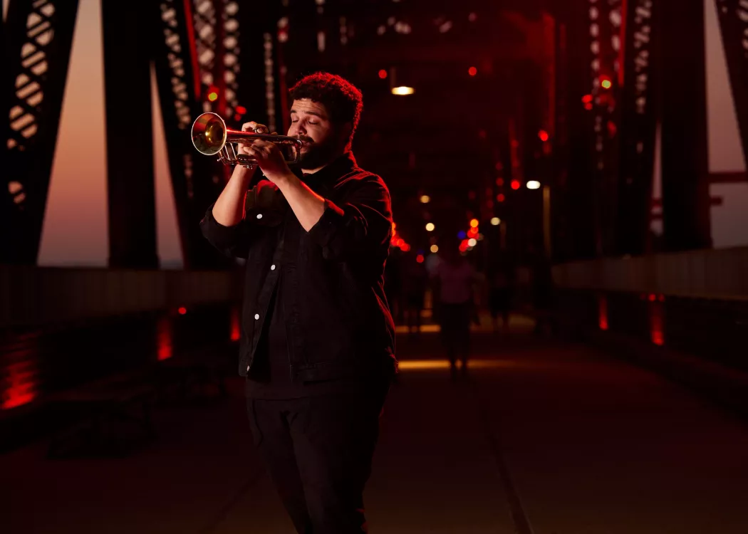 Connor May can be seen playing his trumpet on Big Four Bridge during the sunset.