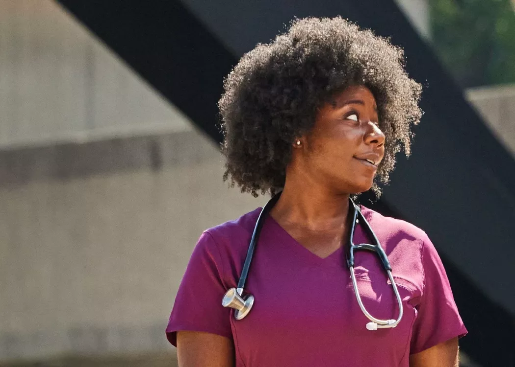 A woman in purple medical scrubs having a conversation outside.