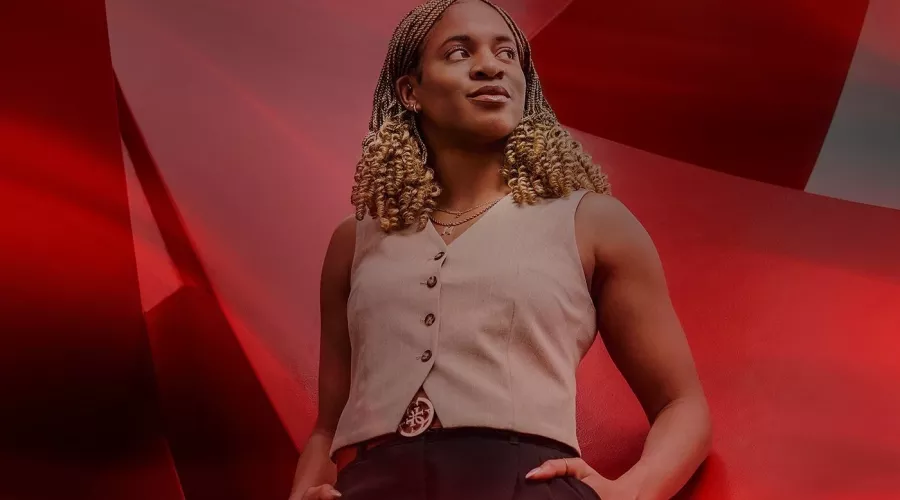 A young woman confidently leaning against a large red sculpture.