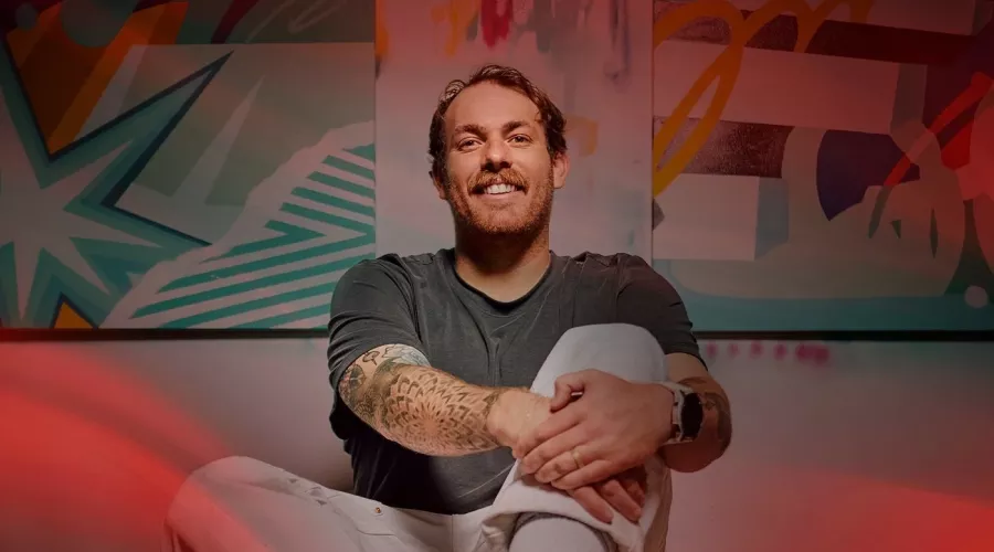 A smiling man surrounded by spray paint cans in an art studio.