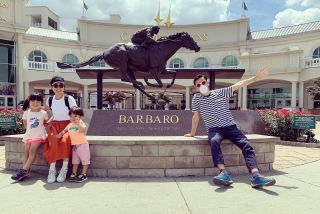family posing in front of race horse statue