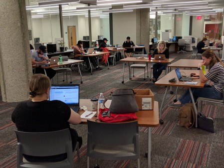 several writers sitting at tables concentrating on their laptops or papers 