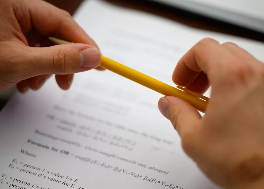 Close-up of a student holding a pencil over course material